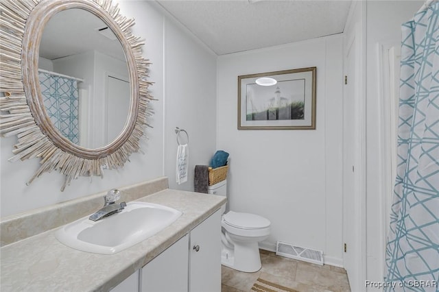 bathroom featuring vanity, tile patterned flooring, a textured ceiling, and toilet