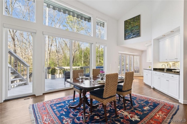 dining area with light wood-style floors and high vaulted ceiling