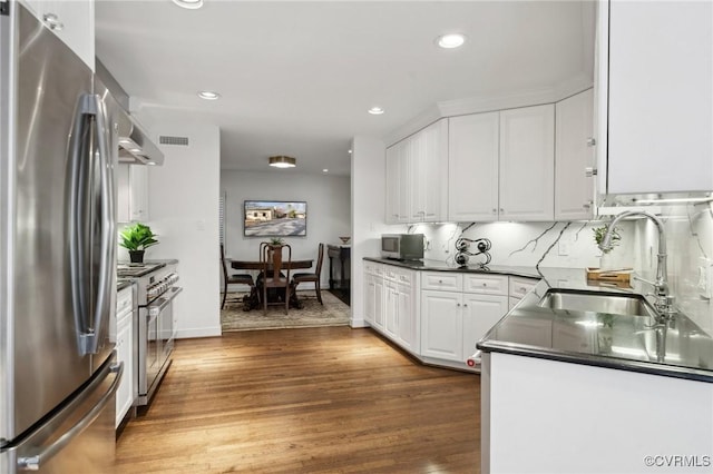 kitchen featuring dark wood-style floors, dark countertops, appliances with stainless steel finishes, white cabinets, and a sink