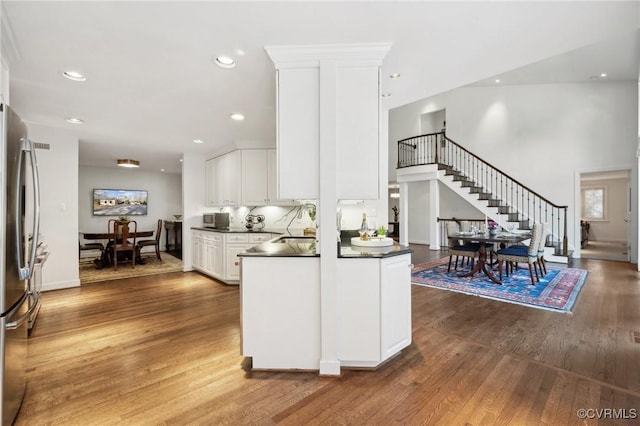 kitchen with freestanding refrigerator, white cabinetry, dark countertops, and wood finished floors