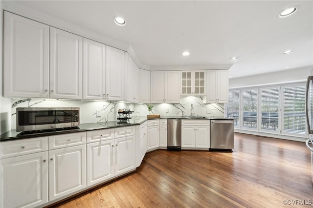 kitchen with dark wood-style flooring, dark countertops, appliances with stainless steel finishes, glass insert cabinets, and white cabinetry