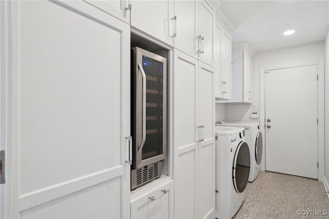 clothes washing area with cabinet space, wine cooler, washing machine and clothes dryer, light floors, and recessed lighting