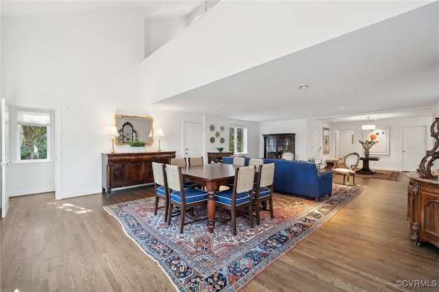 dining space featuring a high ceiling, baseboards, wood finished floors, and recessed lighting