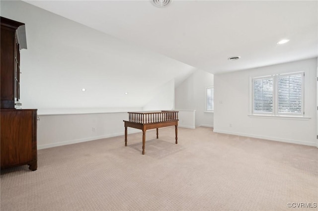 interior space featuring baseboards, vaulted ceiling, and light colored carpet