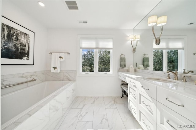 bathroom with marble finish floor, a healthy amount of sunlight, vanity, and a bath