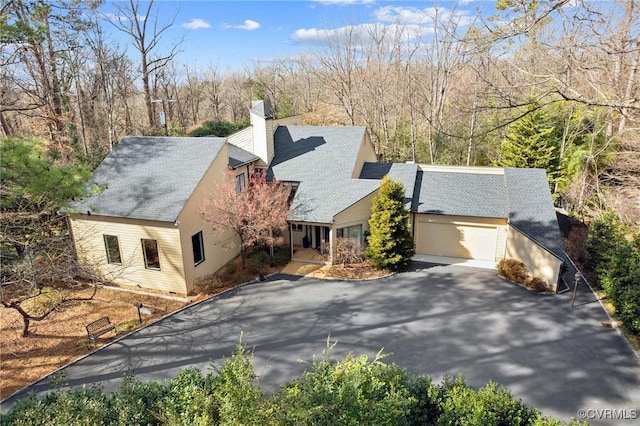 view of front of house featuring a garage, a chimney, and aphalt driveway