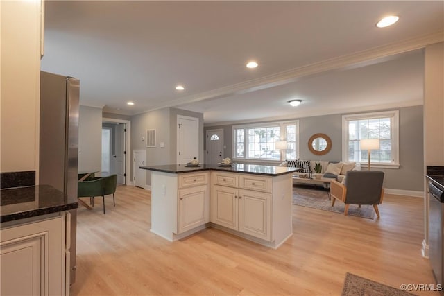 kitchen featuring crown molding, dark stone counters, stainless steel appliances, and light wood-type flooring