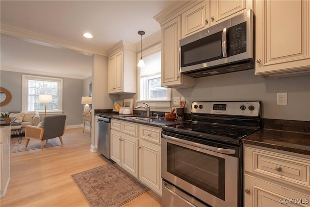 kitchen with sink, decorative light fixtures, cream cabinets, and stainless steel appliances