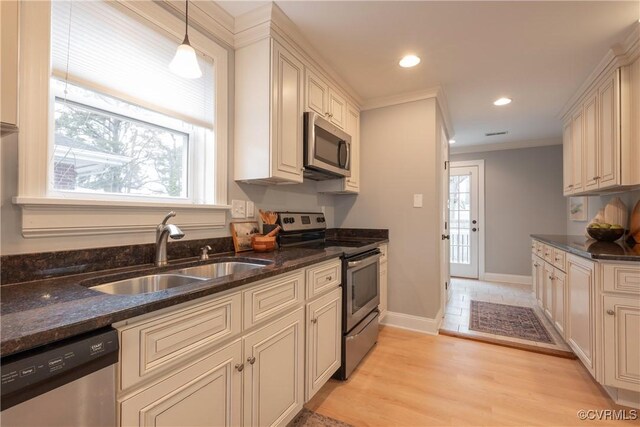 kitchen featuring stainless steel appliances, hanging light fixtures, sink, and dark stone countertops