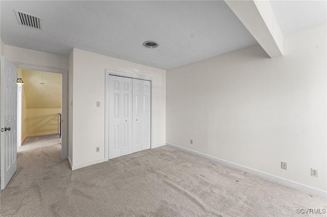 unfurnished bedroom with light colored carpet and a closet