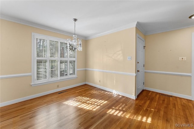 spare room with hardwood / wood-style flooring, ornamental molding, and a notable chandelier