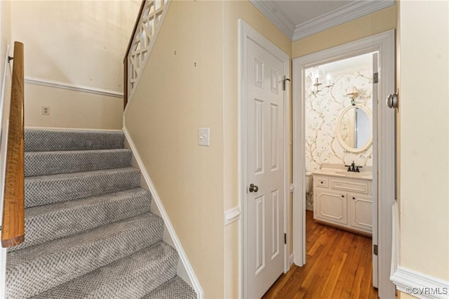 staircase featuring ornamental molding, sink, and wood-type flooring