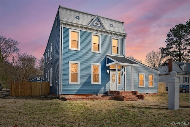 view of front of home with entry steps, a lawn, and fence