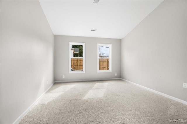 spare room featuring visible vents, baseboards, and light colored carpet