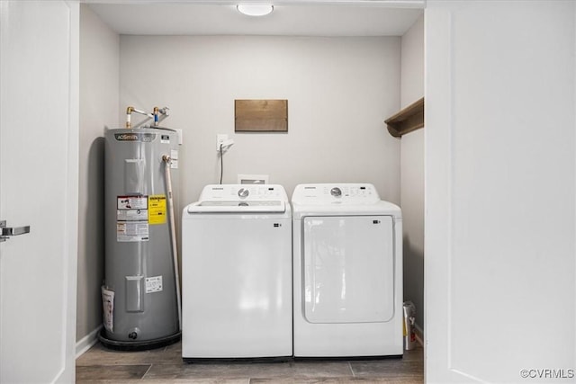 clothes washing area featuring laundry area, baseboards, wood tiled floor, washer and dryer, and water heater