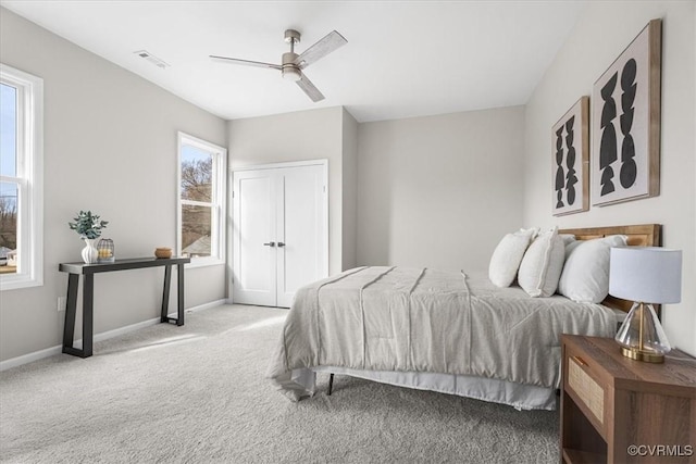 carpeted bedroom with visible vents, a closet, baseboards, and a ceiling fan