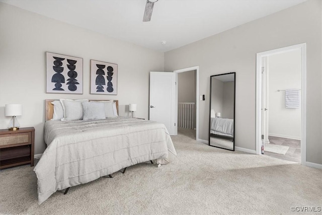 bedroom with baseboards, ensuite bath, a ceiling fan, and light colored carpet