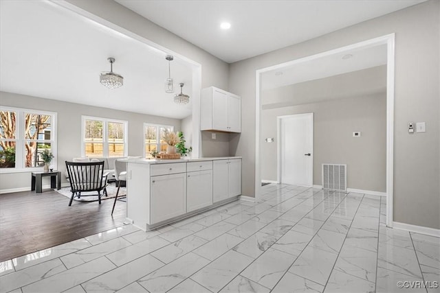 kitchen with marble finish floor, light countertops, pendant lighting, and white cabinets