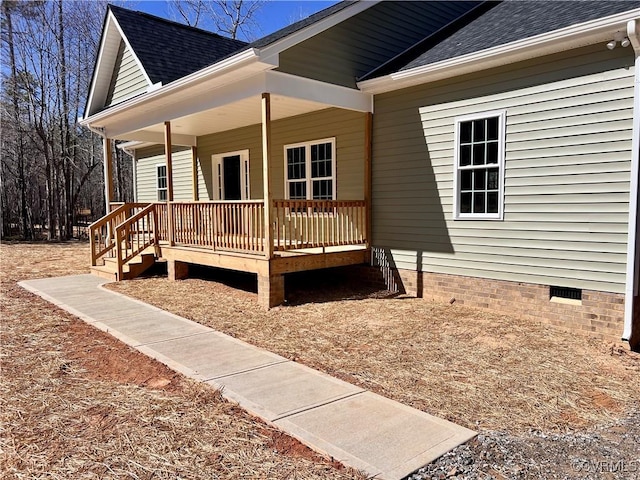 view of side of property featuring covered porch, crawl space, and a shingled roof