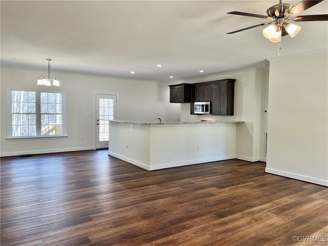 kitchen featuring stainless steel microwave, crown molding, baseboards, and dark wood finished floors