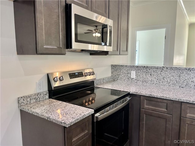 kitchen featuring dark brown cabinetry, light stone counters, a ceiling fan, and appliances with stainless steel finishes