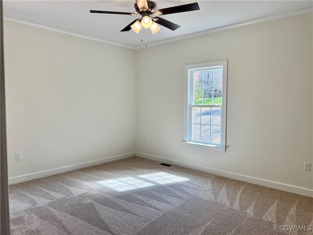 carpeted empty room with baseboards, visible vents, ceiling fan, and ornamental molding