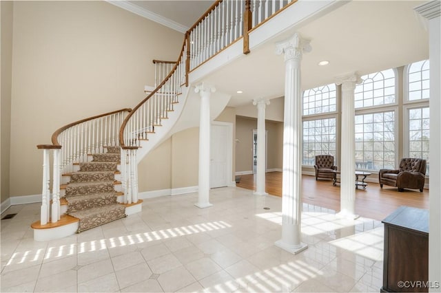 interior space with crown molding, decorative columns, and a high ceiling