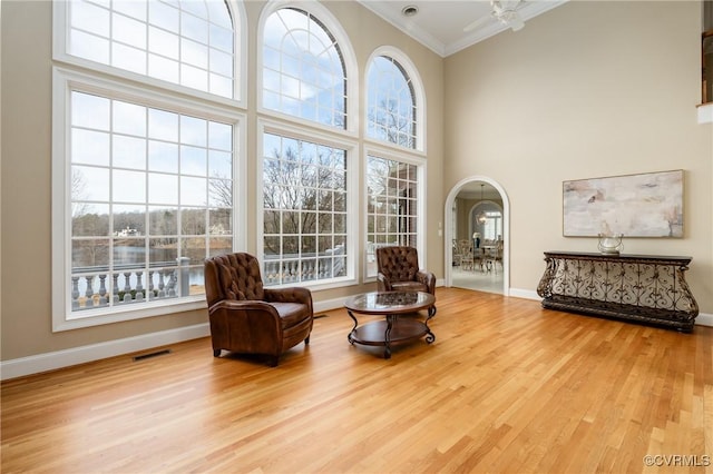 living area with crown molding, wood-type flooring, and a healthy amount of sunlight