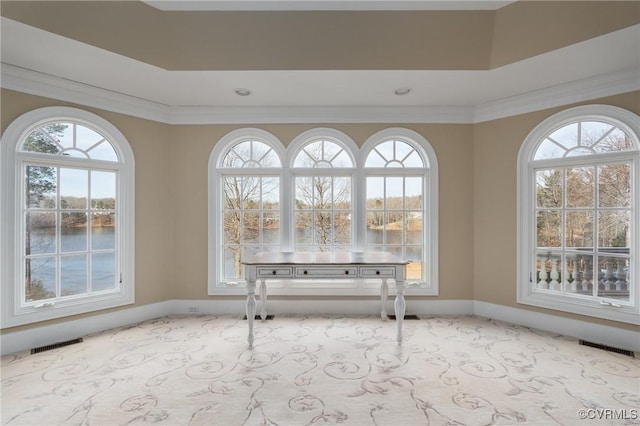 unfurnished dining area with a raised ceiling, crown molding, and light colored carpet