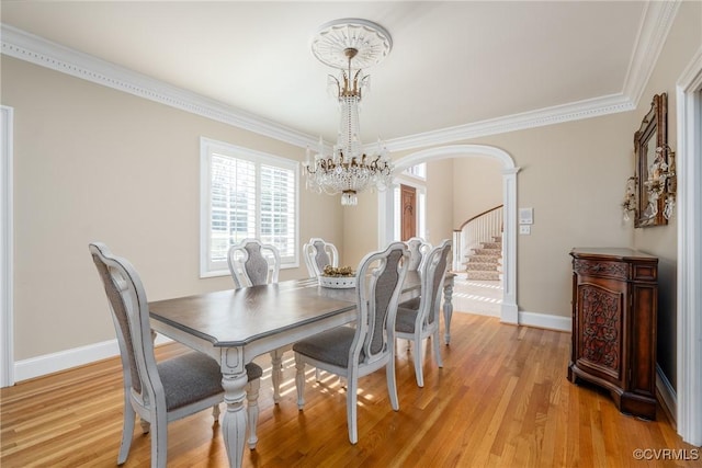 dining space with ornamental molding, a chandelier, and light hardwood / wood-style flooring