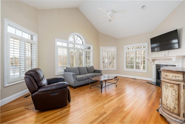 living room with wood-type flooring, high vaulted ceiling, ceiling fan, and a fireplace