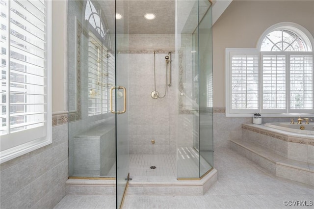 bathroom with tile patterned flooring, plus walk in shower, and tile walls