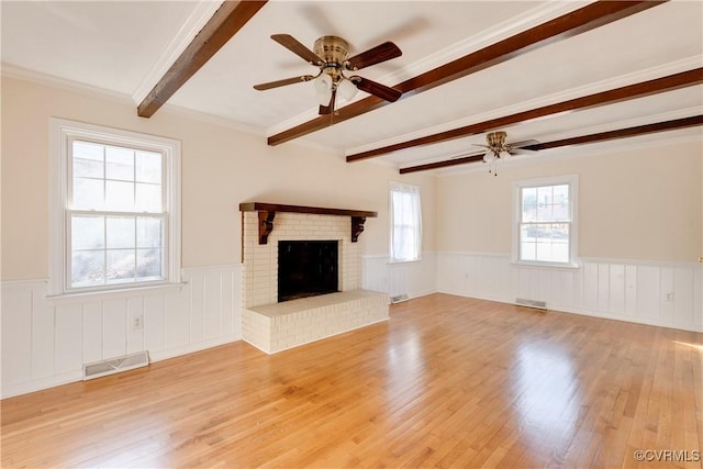 unfurnished living room featuring a brick fireplace, light hardwood / wood-style flooring, beamed ceiling, and ceiling fan