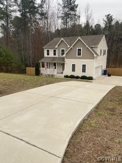 view of front facade with a garage, a porch, concrete driveway, and a front yard