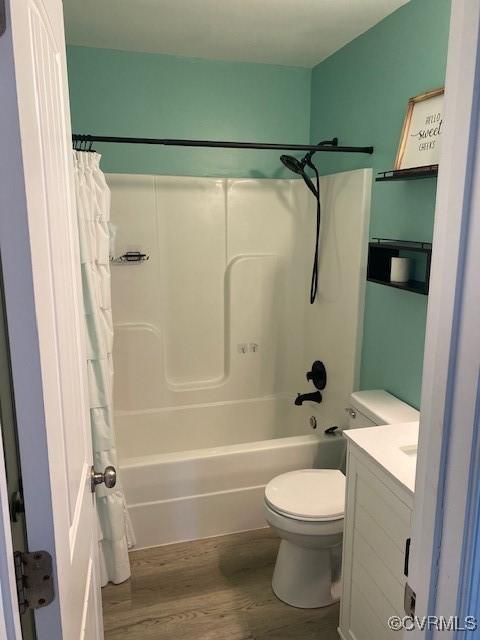 bathroom with vanity, shower / bath combination with curtain, wood finished floors, and toilet