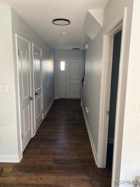 hallway featuring dark wood-style flooring and baseboards