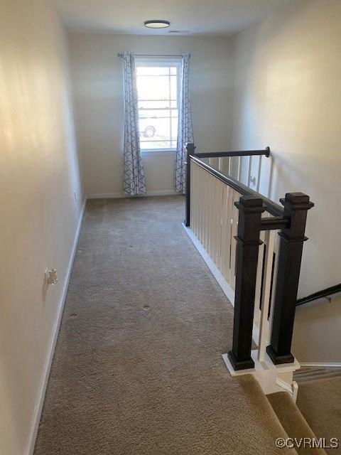 corridor with carpet floors, an upstairs landing, and baseboards