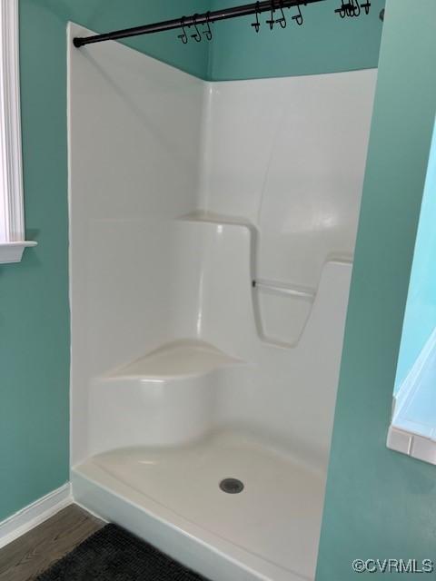 full bathroom featuring a shower, wood finished floors, and baseboards