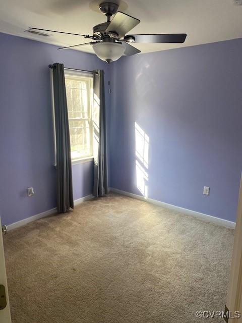 carpeted empty room featuring visible vents, baseboards, and a ceiling fan