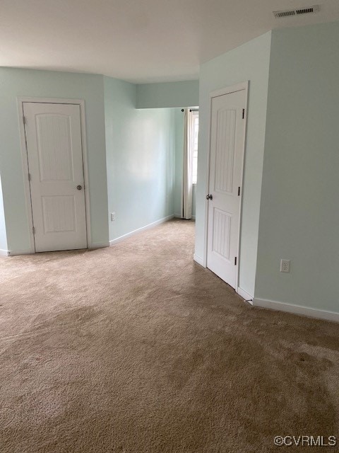 unfurnished room with carpet floors, visible vents, and baseboards