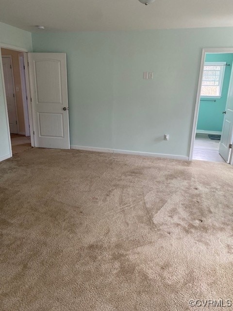 unfurnished room with carpet and baseboards