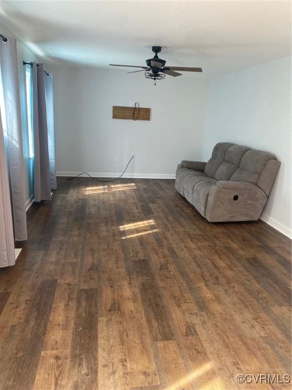 unfurnished living room with a ceiling fan, dark wood finished floors, and baseboards