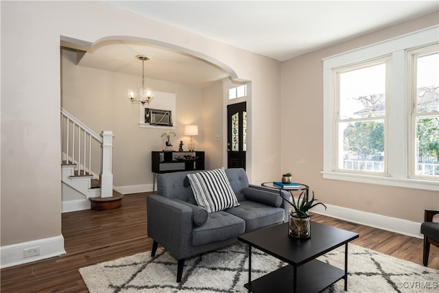 living room featuring dark wood-type flooring, a wall mounted AC, and a notable chandelier