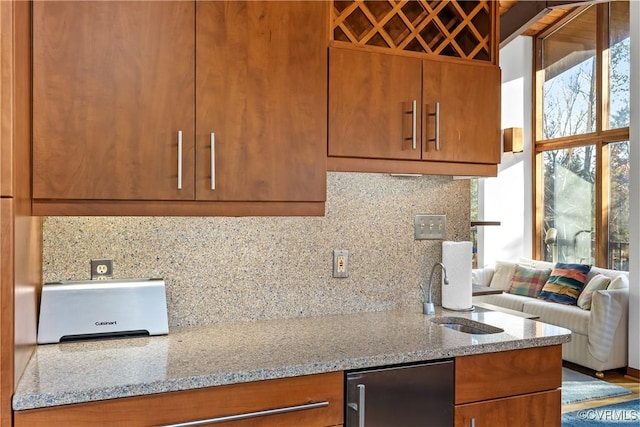 kitchen with fridge, light stone countertops, sink, and backsplash