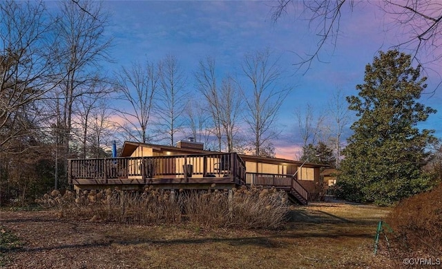 back house at dusk featuring a wooden deck