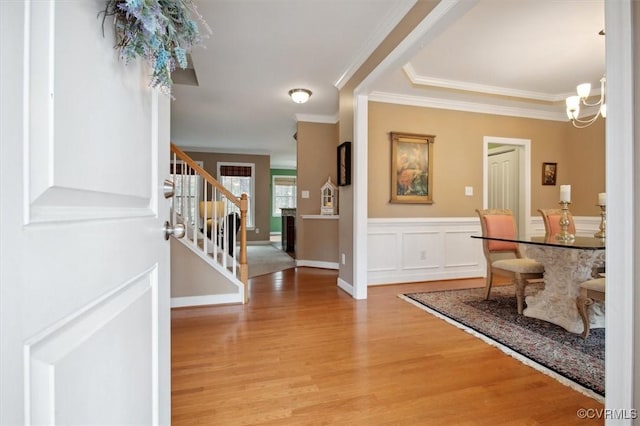 foyer entrance with crown molding, an inviting chandelier, and light hardwood / wood-style floors