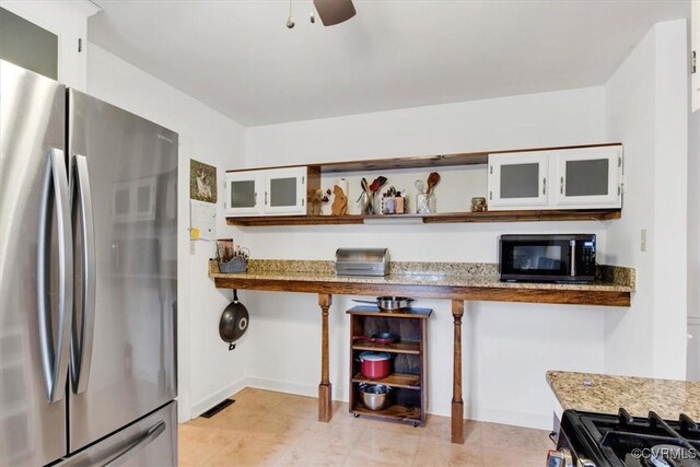 1270 Riverview Dr, West Point, VA 23181 - kitchen with freestanding refrigerator, black microwave, gas stove, open shelves, and glass insert cabinets