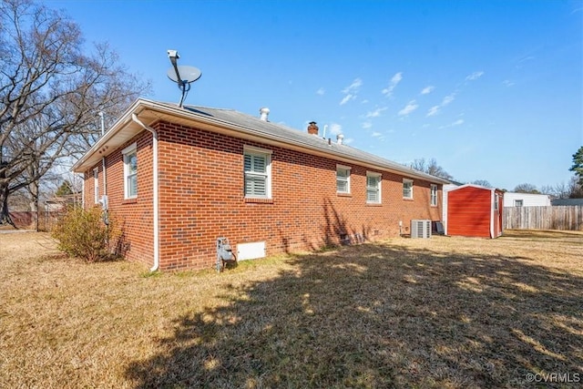 exterior space with a yard, central AC unit, and a storage unit