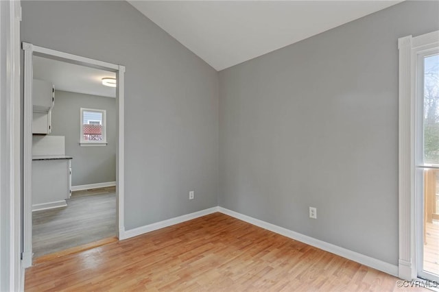 spare room featuring vaulted ceiling and light hardwood / wood-style flooring