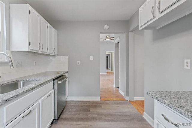 kitchen with sink, white cabinetry, dishwasher, light stone countertops, and backsplash